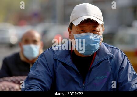 Peking, China. April 2020. Chinesen, die Schutzmasken tragen, fahren am Donnerstag, 9. April 2020 in Peking mit dem Fahrrad. Chinas Hauptstadt bremst die Rückkehr zu einem "normalen" Leben von drakonischen Sicherheitsmaßnahmen aufgrund des Covid-19-Ausbruchs, da die Regierung langsam einige Einschränkungen für Reisen und soziale Interaktionen aufhebt. Foto von Stephen Shaver/UPI Credit: UPI/Alamy Live News Stockfoto