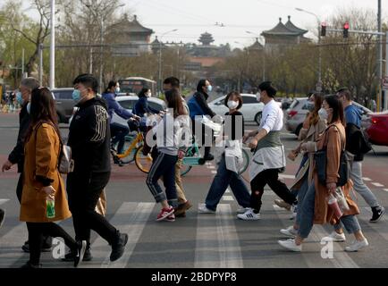 Peking, China. April 2020. Chinesen, die Schutzmasken tragen, gehen am Donnerstag, den 9. April 2020 durch eine Kreuzung im Zentrum Pekings. Chinas Hauptstadt bremst die Rückkehr zu einem "normalen" Leben von drakonischen Sicherheitsmaßnahmen aufgrund des Covid-19-Ausbruchs, da die Regierung langsam einige Einschränkungen für Reisen und soziale Interaktionen aufhebt. Foto von Stephen Shaver/UPI Credit: UPI/Alamy Live News Stockfoto