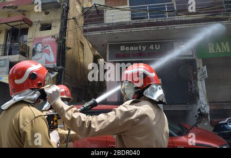 Neu-Delhi, Indien. April 2020. Ein Feuerwehrmann passt die Schutzausrüstung eines anderen Sprühdesinfizierers in einem Wohngebiet in Neu-Delhi, Indien an, während die Covid-19 Corona-Virus-Fälle weiterhin täglich steigen. (Foto von Sondeep Shankar/Pacific Press) Credit: Pacific Press Agency/Alamy Live News Stockfoto