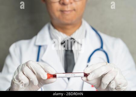 Nahaufnahme der hände asiatischer männlicher Ärzte. Er nimmt Blut von Coronavirus des Patienten im Reagenzglas am Krankenhaus. Stockfoto