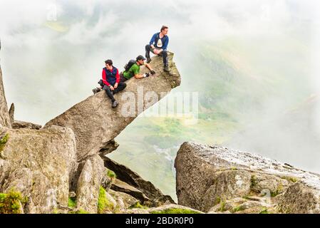 Scrambler auf dem Cannon Stone auf dem Nordgrat von Tryfan, Snowdonia, Wales, mit einem Blick auf Ogwen durch den Nebel Stockfoto