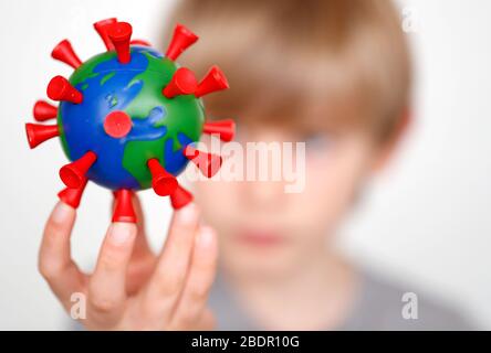 Ein Junge hält ein selbstgemachtes Modell, das die Erde als COVID-19-Molekül darstellt. Stockfoto