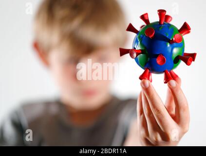 Ein Junge hält ein selbstgemachtes Modell, das die Erde als COVID-19-Molekül darstellt. Stockfoto