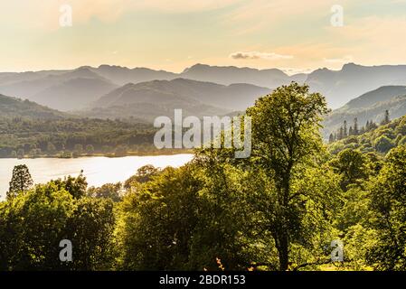 Blick über Windermere von der Skelghyll Lane im English Lake District. Crinkle Crags, Bowfell und die Langdale Pikes auf der Skyline. Stockfoto