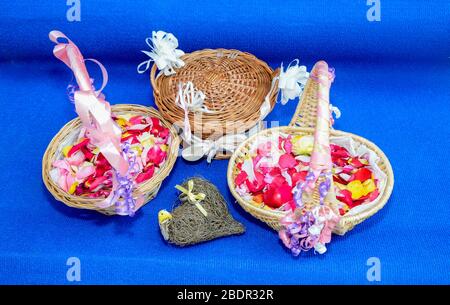 Set von Körben mit Blütenblättern und Herz mit Ringen auf blauem Hintergrund. Stockfoto