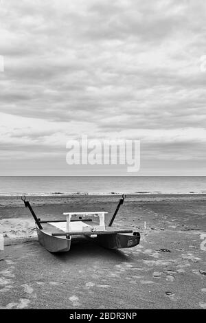 Sicherheitsboot - Katamaran am Meer am leeren Strand in Rimini in der Saison, Italien - minimalistische Landschaft, Schwarz-Weiß-Fotografie Stockfoto