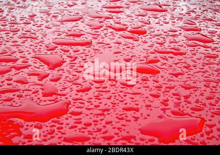 Schließen von Wassertropfen bilden ein abstraktes Muster auf einem starken roten Hintergrund Stockfoto