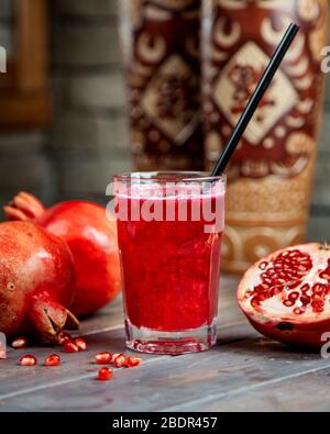 Granatapfelsaft im Glas mit Pfeife Stockfoto