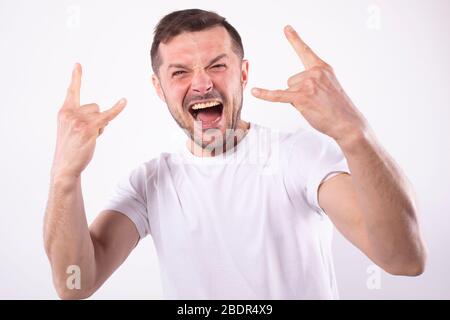 Der Mensch freut sich über den Sieg mit einem breiten Lächeln. Hände in Rockon-Pose. Sportfan-Konzept Stockfoto