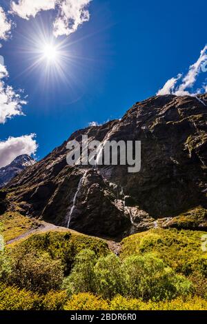 Sunburst und Wasserfälle in den Bergen am Monkey Creek im Hollyford Valley, Southland, Neuseeland Stockfoto