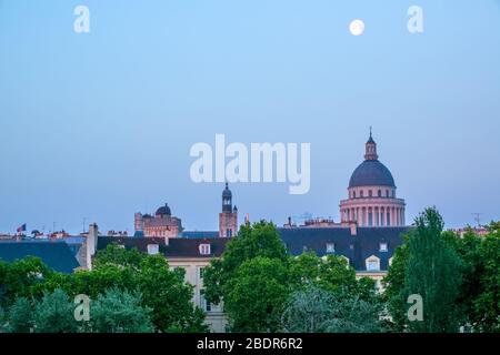 Frankreich. Ein früher Sommermorgen über den Dächern von Paris. Vollmond am blauen Himmel Stockfoto