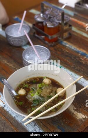 Reisnudeln Suppe mit Fleischball in einer Schüssel essen von Essstäbchen, asiatische Lebensmittel, Thai-Stil, Angle View. Kaltes Wasser Stockfoto