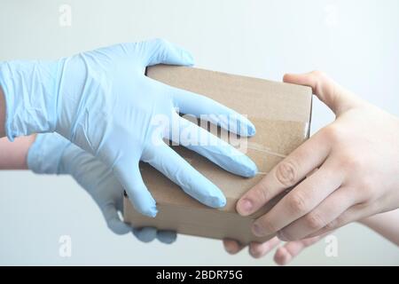 Liefermann hält Pappkartons in medizinischen Gummihandschuhen. Schnelle und kostenlose Lieferung Transport . Kopierbereich. Online-Shopping und Expressversand. Cl Stockfoto
