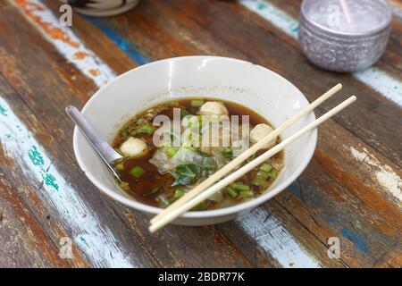 Schüssel mit Reisnudeln Suppe mit Fleischball in einer Schüssel essen von Essstäbchen, asiatische Lebensmittel, Thai-Stil, Angle View Stockfoto