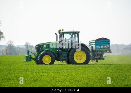 Nicht erkennbarer Landwirt, der Traktor und Dünger auf Weizenfeld in Perry Green, Much Hadham, Hertfordshire treibt. GROSSBRITANNIEN Stockfoto