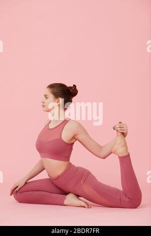 Fit Frau in rosa Sportbekleidung Yoga Übung auf rosa Hintergrund zu üben Stockfoto
