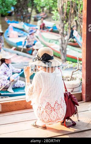 Ein Tourist fotografiert die einheimischen Frauen, die die Bootsfahrt durch die Dschungelflüsse am Rande des Tonle SAP Sees, Kampong Phluk, Kambodscha anbieten. Stockfoto