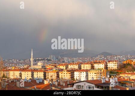 Ankara / Türkei - 2. April 2020: Nach einem regnerischen Tag schaut die Spitze des Regenbogens durch die Wolken. Panoramablick auf Ankara Stadt und einen schönen Hügel Stockfoto