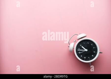 Hohe Winkelansicht des Weckers auf rosa. Stockfoto