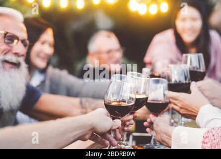 Happy Family Dining und Toasting Rotweingläser in Grill Dinner Party - Menschen, die Spaß beim gemeinsamen Essen Stockfoto