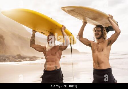 Glückliche Freunde gemeinsam auf dem tropischen Ozean surfen - Sportliche Menschen haben Spaß während des Urlaubs Surf Day - Extreme Sport Lifestyle Konzept Stockfoto