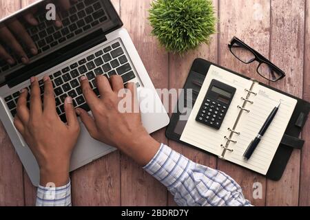 Aus einem hohen Winkel sehen Sie den jungen Mann, der auf einem Laptop tippt. Stockfoto