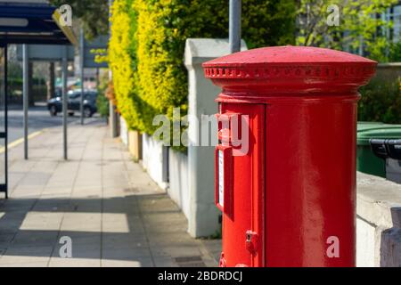 Ein roter königlicher Briefkasten auf einer leeren Straße Stockfoto