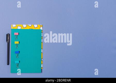 Stapel von hellen Notebooks und Schreibwaren auf blauem Schreibtisch. Kopierbereich. Freier Speicherplatz. Stockfoto