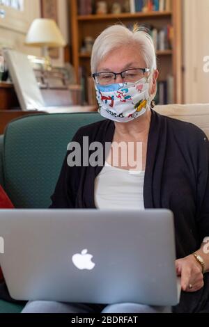 Detroit, Michigan, USA. April 2020. Susan Newell, 71, trägt eine Homemake-Gesichtsmaske zum Schutz vor dem Coronavirus während eines Zoom-Meetings. Kredit: Jim West/Alamy Live News Stockfoto