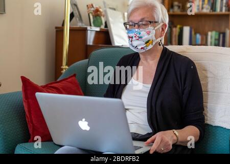 Detroit, Michigan, USA. April 2020. Susan Newell, 71, trägt eine Homemake-Gesichtsmaske zum Schutz vor dem Coronavirus während eines Zoom-Meetings. Kredit: Jim West/Alamy Live News Stockfoto