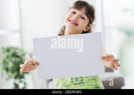 Süßes fröhliches Mädchen mit einem leeren Schild und lächelnder Inneneinrichtung im Hintergrund Stockfoto