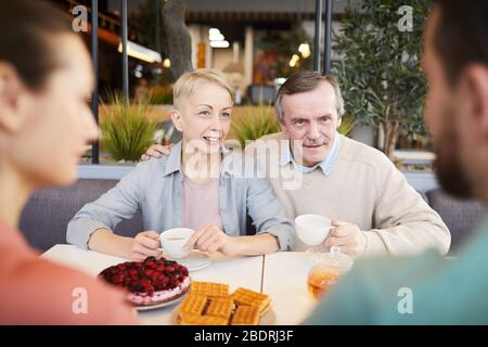 Reifes Paar sitzt am Tisch Tee trinken und mit jungen Paar sprechen sie im Café sind Stockfoto
