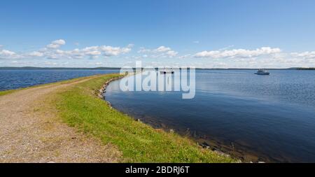 Wellenbrecher und ein kleiner Binnengewässer Fischtrawler ankerten dahinter am See Pohjois-Konnevesi, Finnland Stockfoto