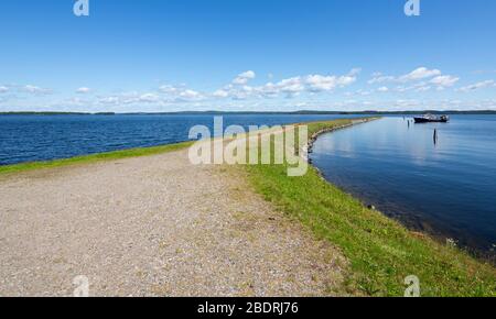 Wellenbrecher und ein kleiner Binnengewässer Fischtrawler ankerten dahinter am See Pohjois-Konnevesi, Finnland Stockfoto
