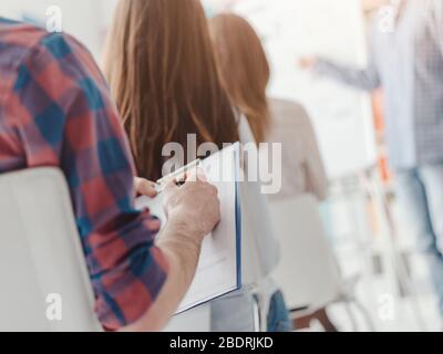 Gruppe von Personen, die an einem Geschäftsseminar teilnehmen und Notizen schreiben, selektiver Fokus Stockfoto