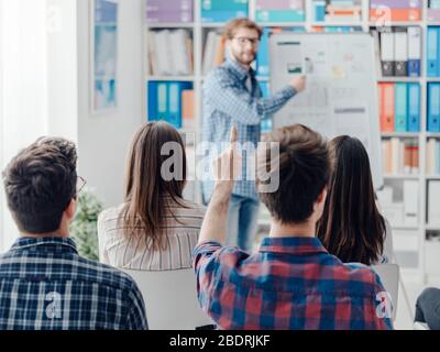 Geschäftspräsentation im Büro: Ein Mann erklärt einer Gruppe von Menschen ein Projekt auf einem Whiteboard Stockfoto