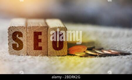 Cubes mit dem Akronym SEO für Suchmaschinen-Optimierung mit Münzen neben. Internet Marketing Konzept Stockfoto
