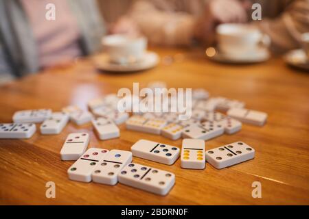 Nahaufnahme des Domino auf dem Holztisch mit Personen im Hintergrund Stockfoto