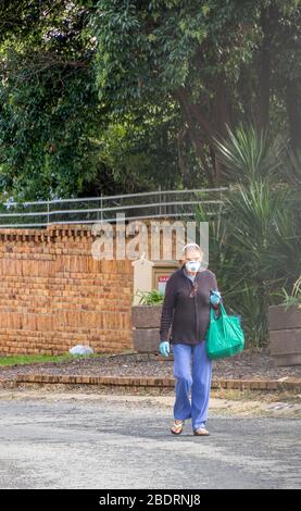 Alberton, Südafrika - unbekannte ältere kaukasische Frau geht während der nationalen Sperre vom Einkaufen nach dem Notwendigsten zurück Stockfoto