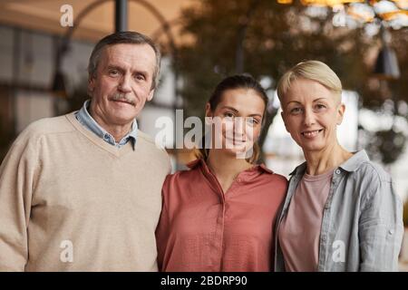 Porträt zweier Eltern, die zusammen mit ihrer Tochter stehen und vor der Kamera lächeln Stockfoto