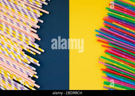 Papier Strohhalme vs Kunststoff-Strohhalme auf buntem Hintergrund.farbige Tubuli für Saft und Cocktails. Event- und Partyzubehör.farbenfrohes Design und abstrakt. Stockfoto