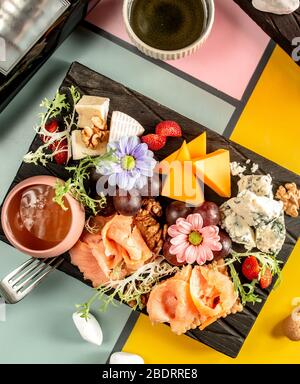 Käseplatte mit Cheddar Parmesan Blauschimmelkäse geräucherter Lachs Traubenhonig und Nüsse Stockfoto