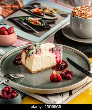 Käsekuchen-Scheibe garniert mit Beerenmarmelade und Stücken Stockfoto