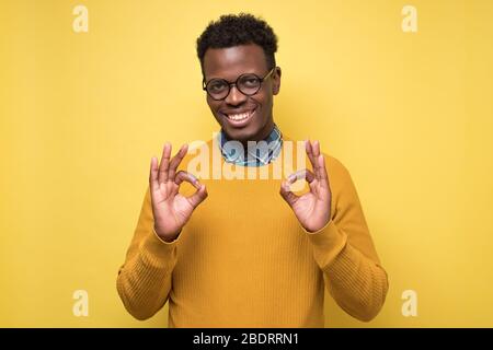 Porträt eines glücklichen afroamerikanischen Mannes in Brille zeigt ok unterschreiben und lächeln Stockfoto