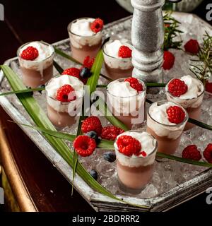 Schokoladenpudding mit Schlagsahne und Himbeere in Schnapsgläsern gekrönt Stockfoto