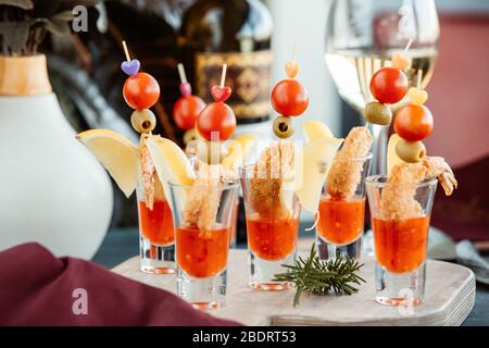 Knusprig gebratene Garnelen in Schnapsgläsern mit süßer Chilisauce und Zitrone serviert Stockfoto