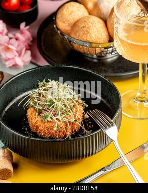 Knusprig paniertes Hähnchenpatty mit Kräutern in schwarzer Schüssel gekrönt Stockfoto