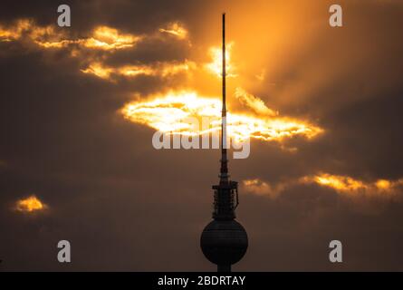 Berlin, Deutschland. April 2020. Die Sonne scheint bei Sonnenuntergang durch die Wolkendecke hinter dem Fernsehturm. Credit: Christophe Gateau / dpa / Alamy Live News Stockfoto
