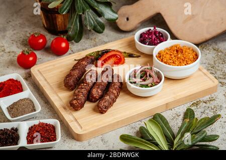 lule Kebab serviert mit Bulgur Schüssel Zwiebelsalat und Rotkohl Gurken Stockfoto