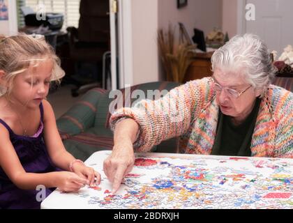 Enkelmutter und Enkelin arbeiten ein Puzzle zusammen Stockfoto